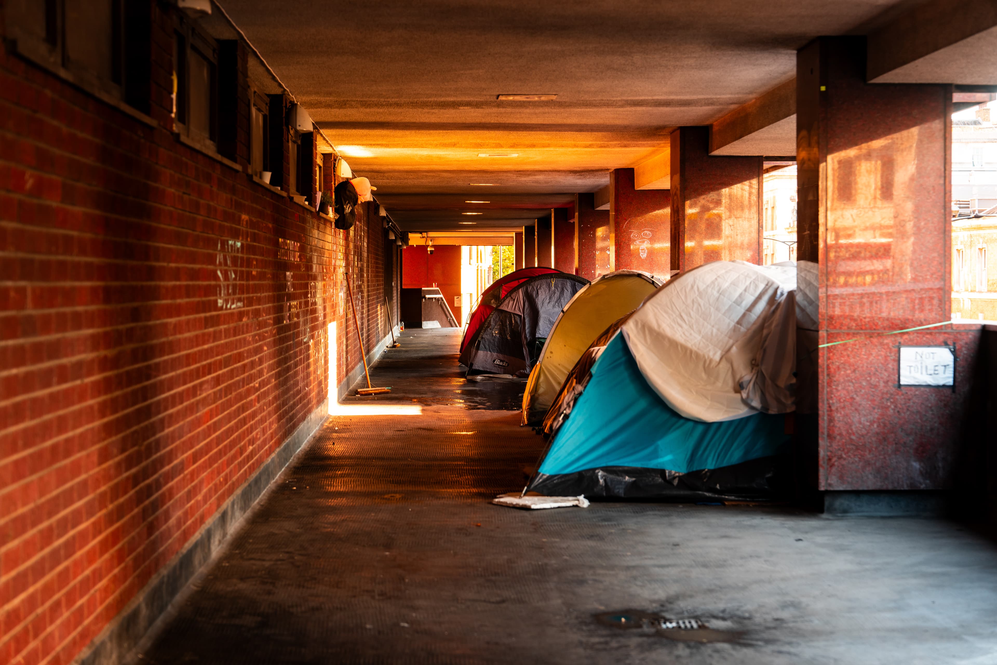 Passage under the residence with row of homeless peoples tents - Europe Confronts Rising Homelessness Crisis - hero image 