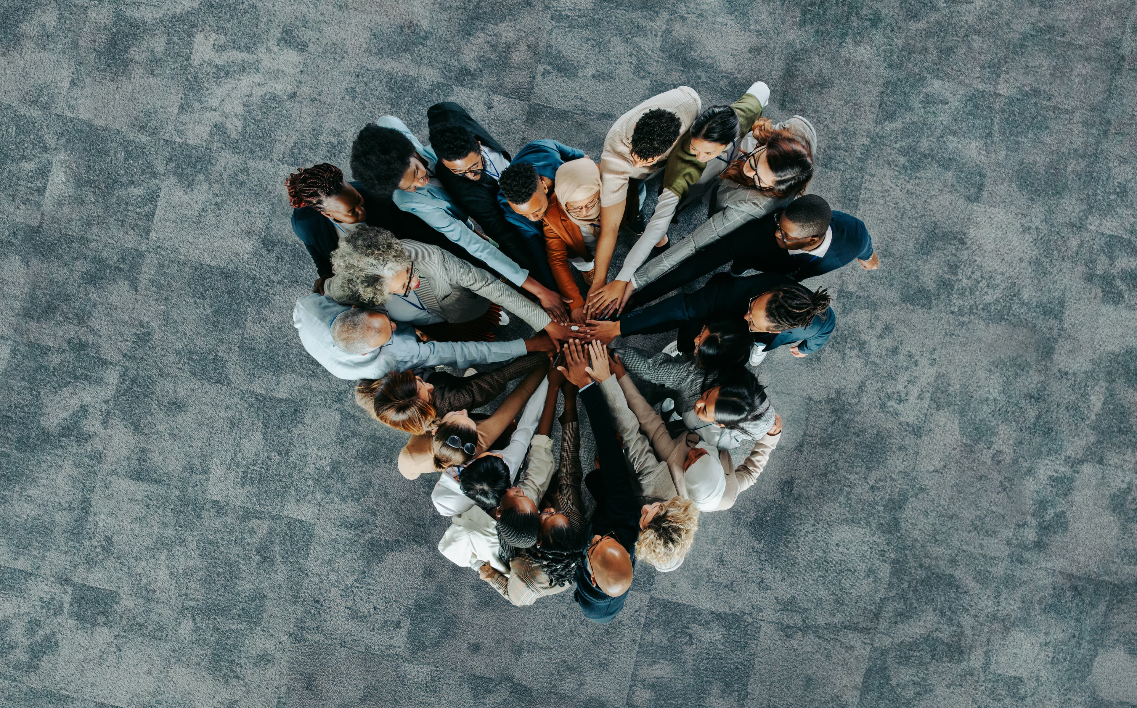 multicultural group of people holding their hands together