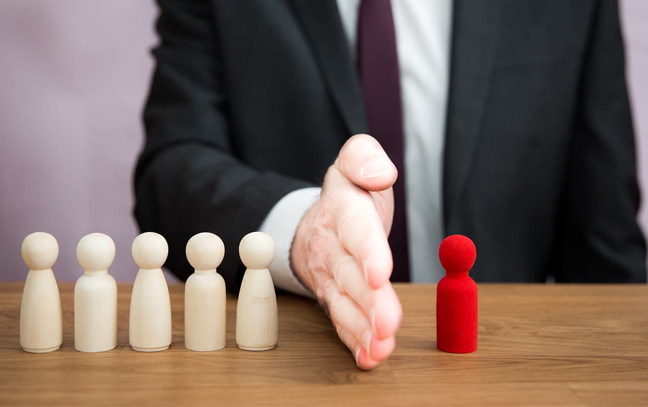 man separating one wooden figure from others 