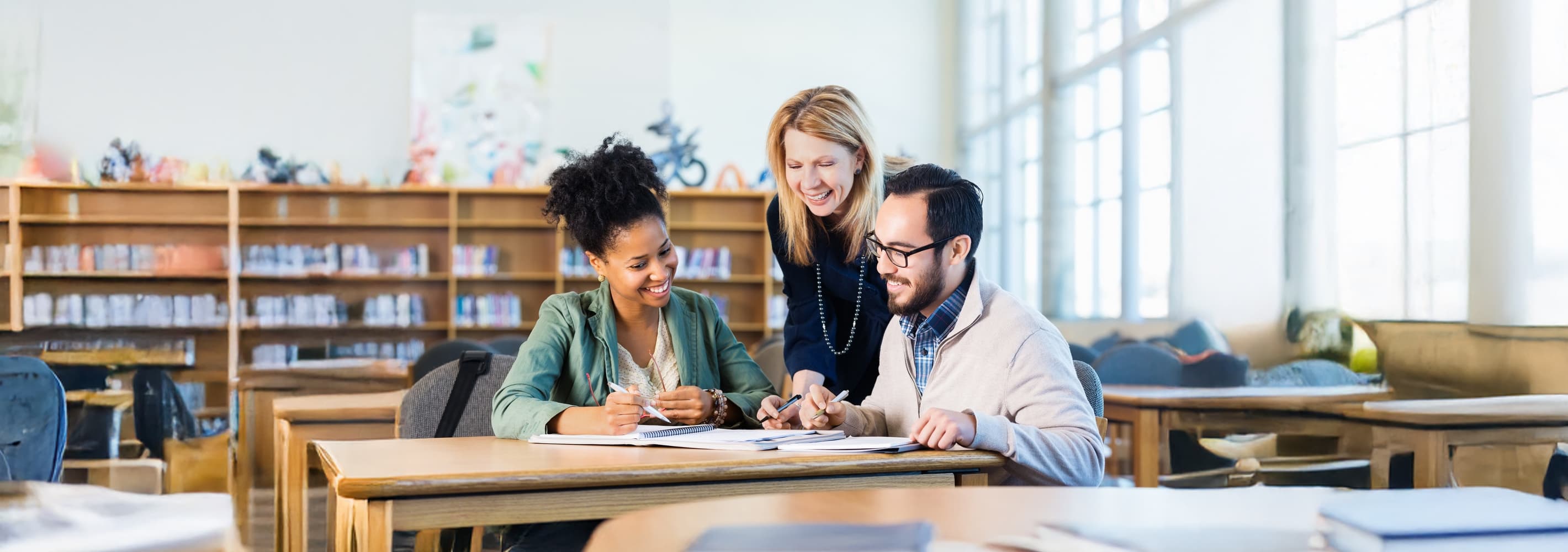 3 People sitting at the desk in the library and collaborationg on the documentation.