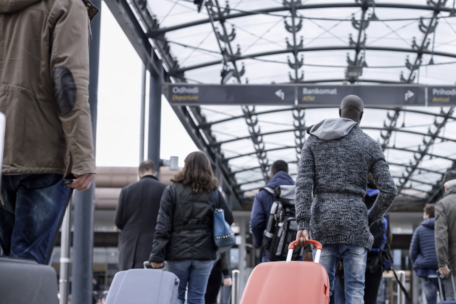 People walking with wheeled luggage on the train station.